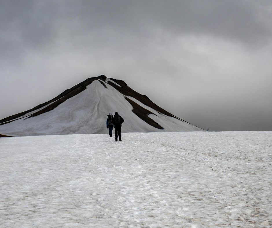 alt" Dois aventureiros caminham na neve durante mais uma etapa de trekking na Islândia"