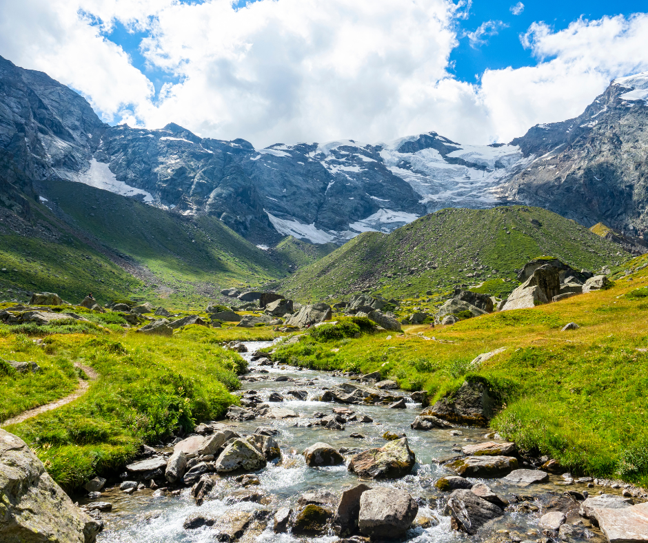 um riacho que atravessa um vale com montanhas cobertas de neve